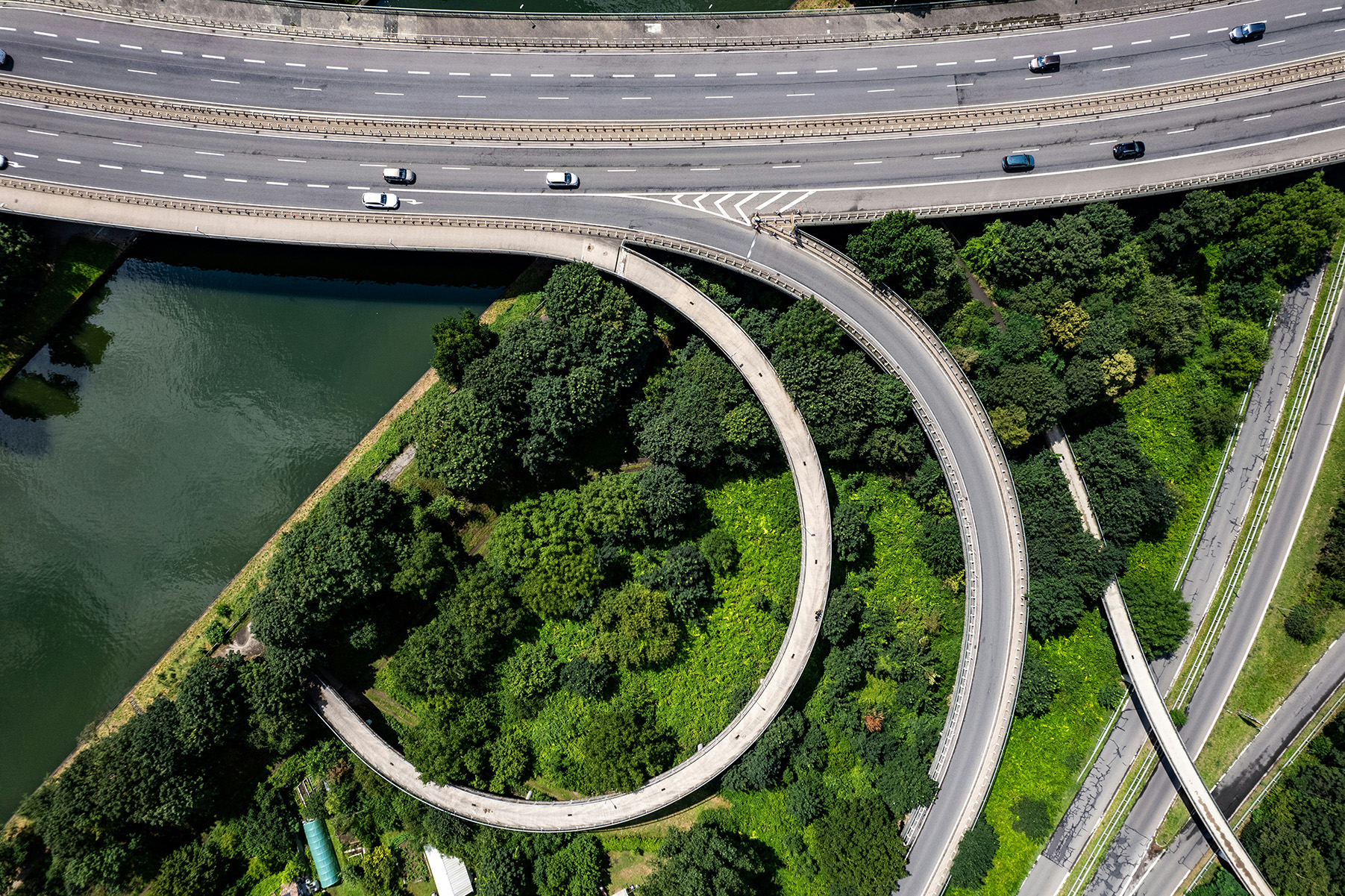 A motorway interchange seen from directly above, beside a canal